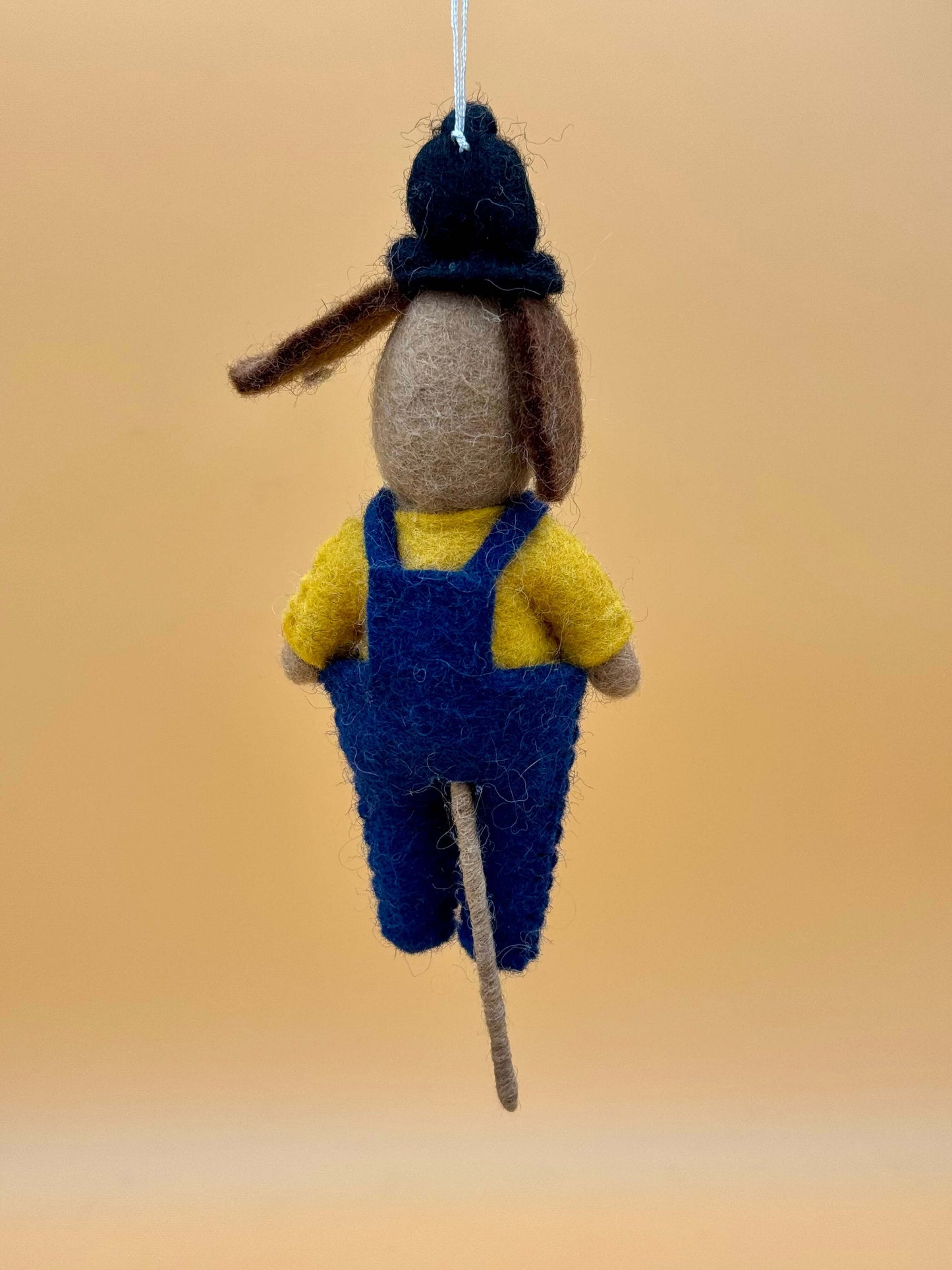 Handgemachter Filzanhänger Schlüsselanhänger als Fahrkartenkontrolleur Hund in blauen Overalls und gelbem Shirt.