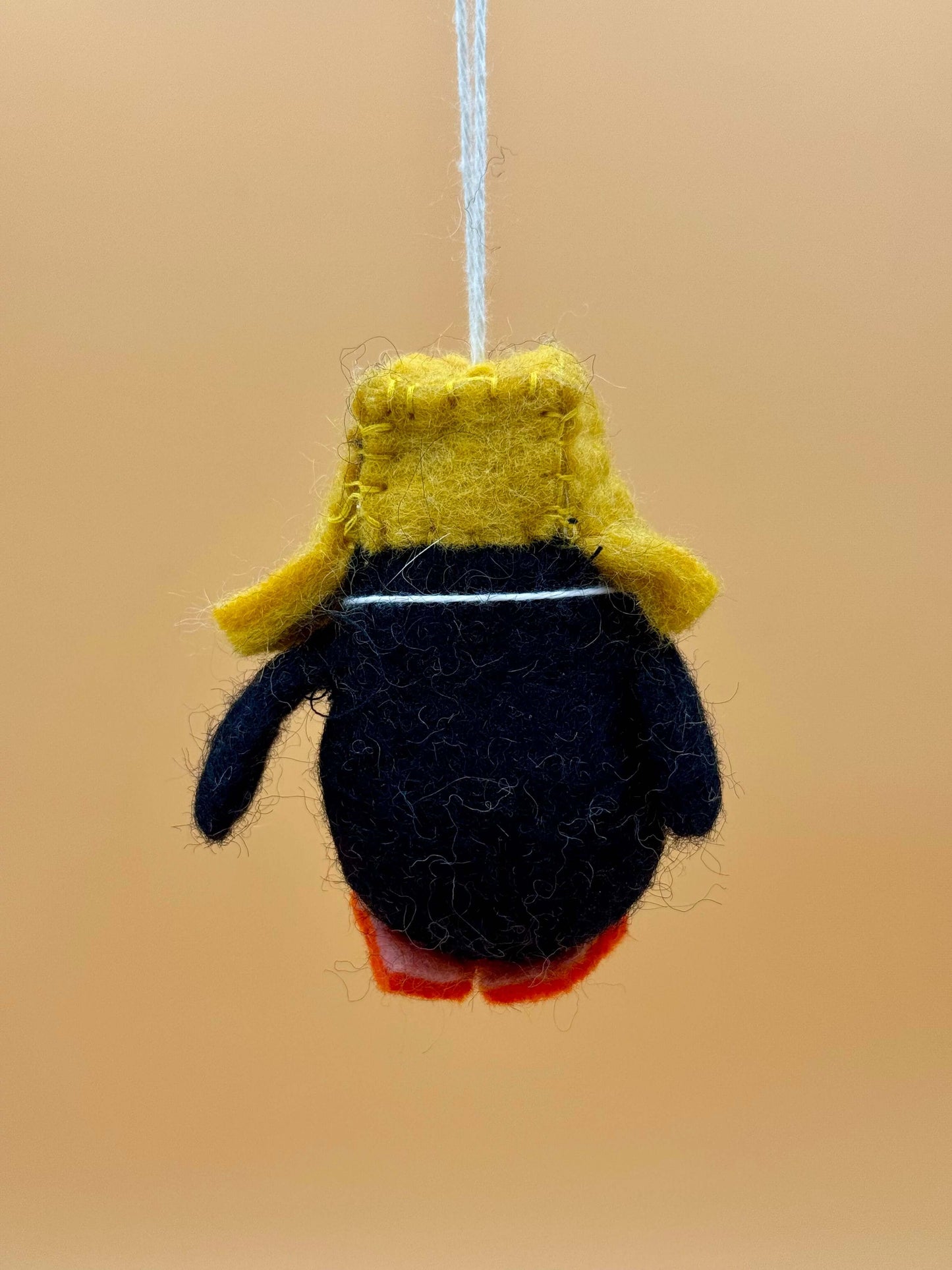 Filzanhänger Schlüsselanhänger Pinguin mit Mütze und Schal in Schwarz, Weiß, Gelb und Orange, handgemacht aus 100% Wolle.