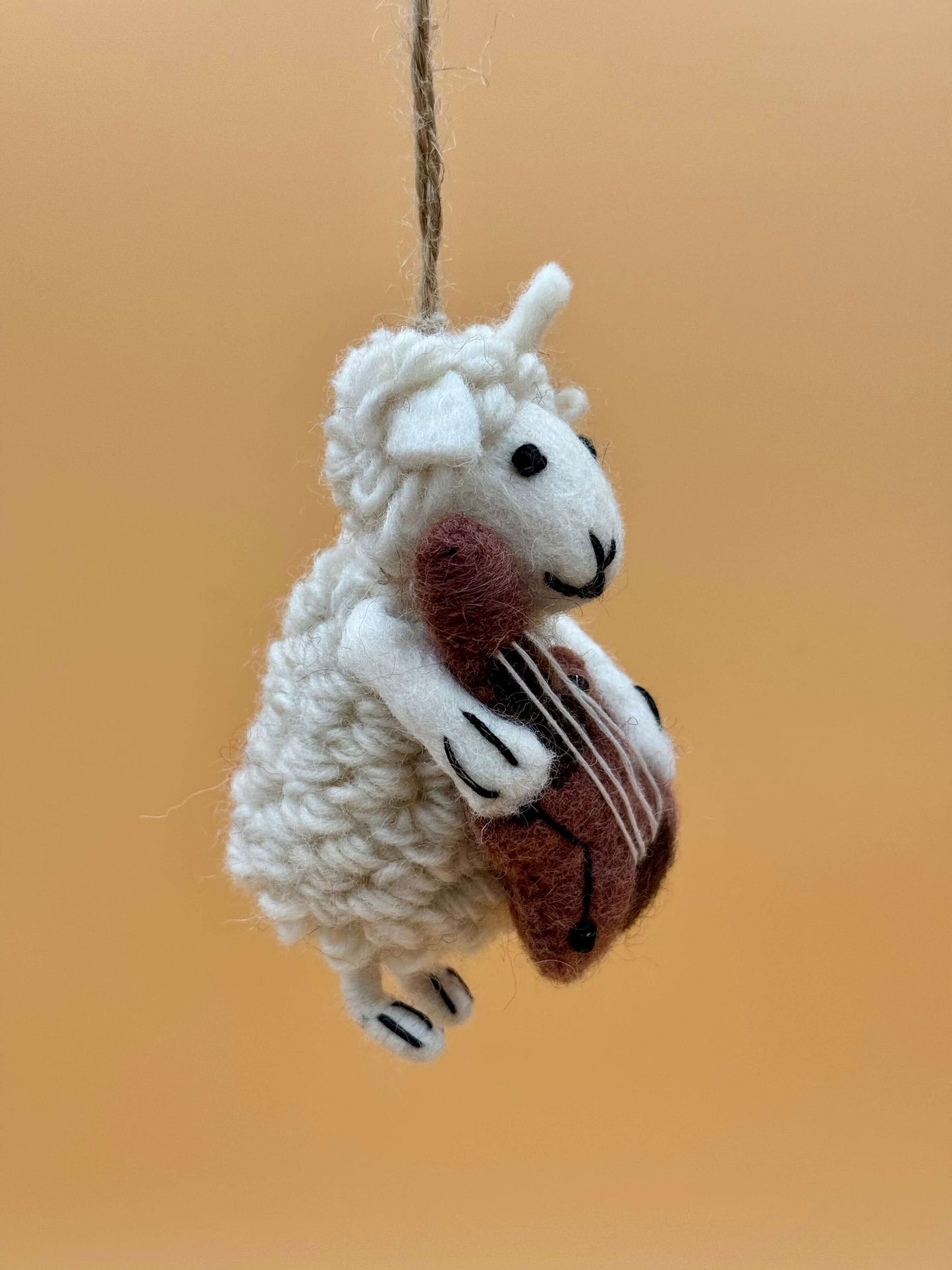 Filzanhänger Schlüsselanhänger Schaf spielt Cello, handgemacht aus Wolle in weiß und braun, einzigartiges Design.
