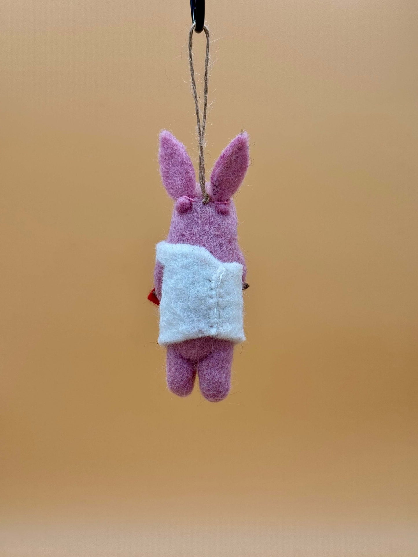 Filzanhänger Schlüsselanhänger in Form eines Schweins mit Bogen und Pfeil, handgefertigt aus Wolle, rosa Farbe.