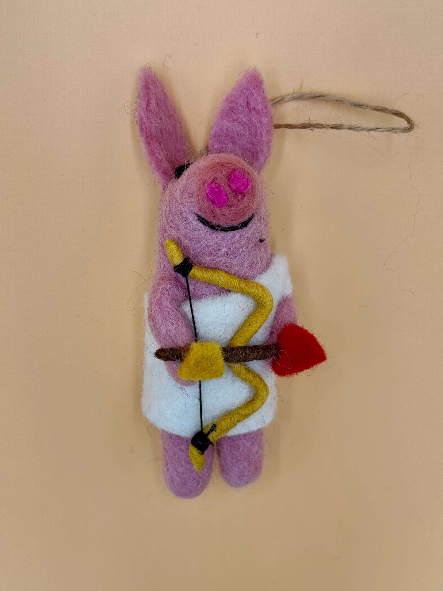 Handgefertigter Filzanhänger Schlüsselanhänger Schwein mit Bogen und Pfeil in rosa und weiß.