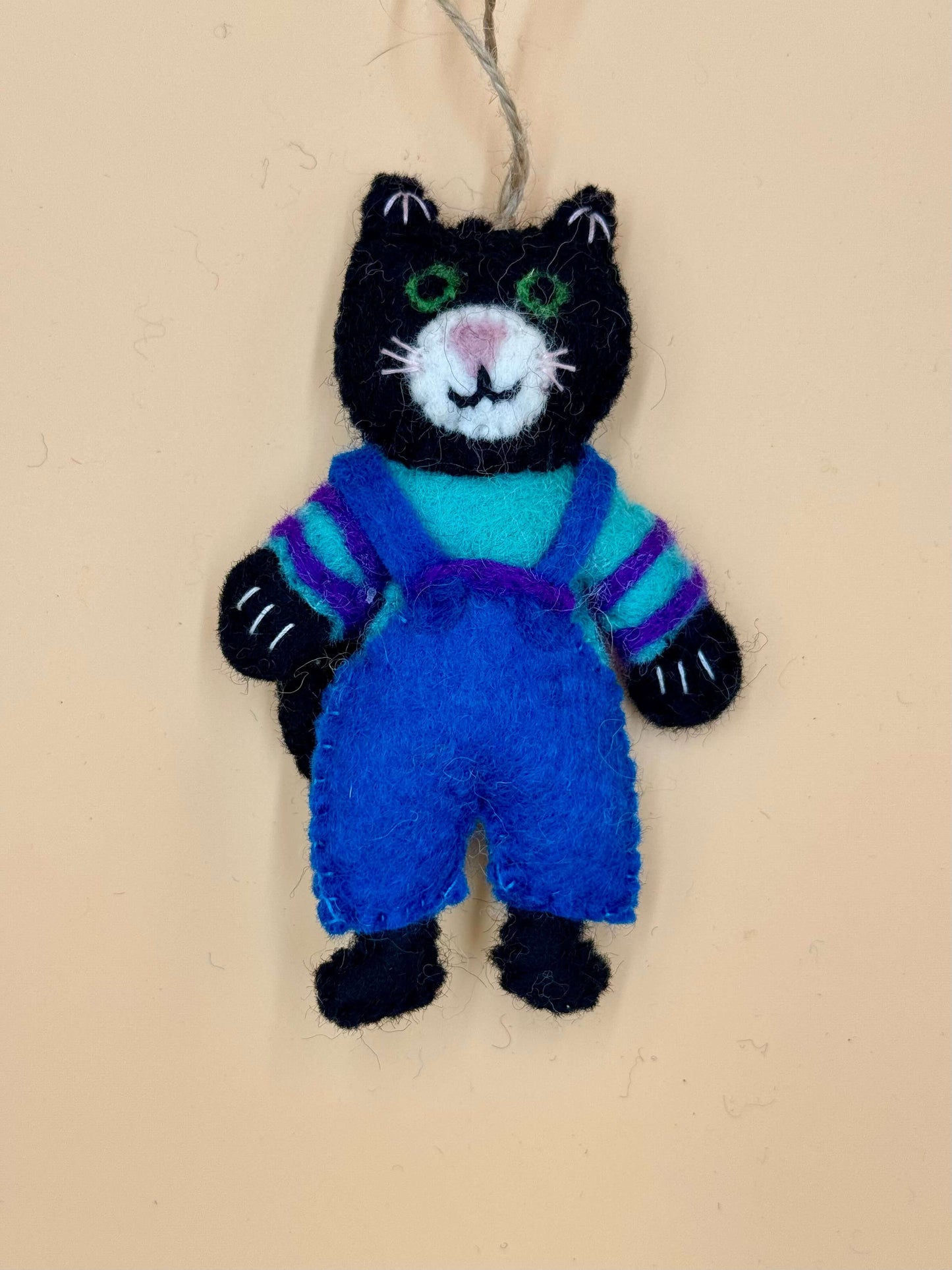 Handmade black cat keychain with blue overalls and colorful stripes, unique felt accessory.