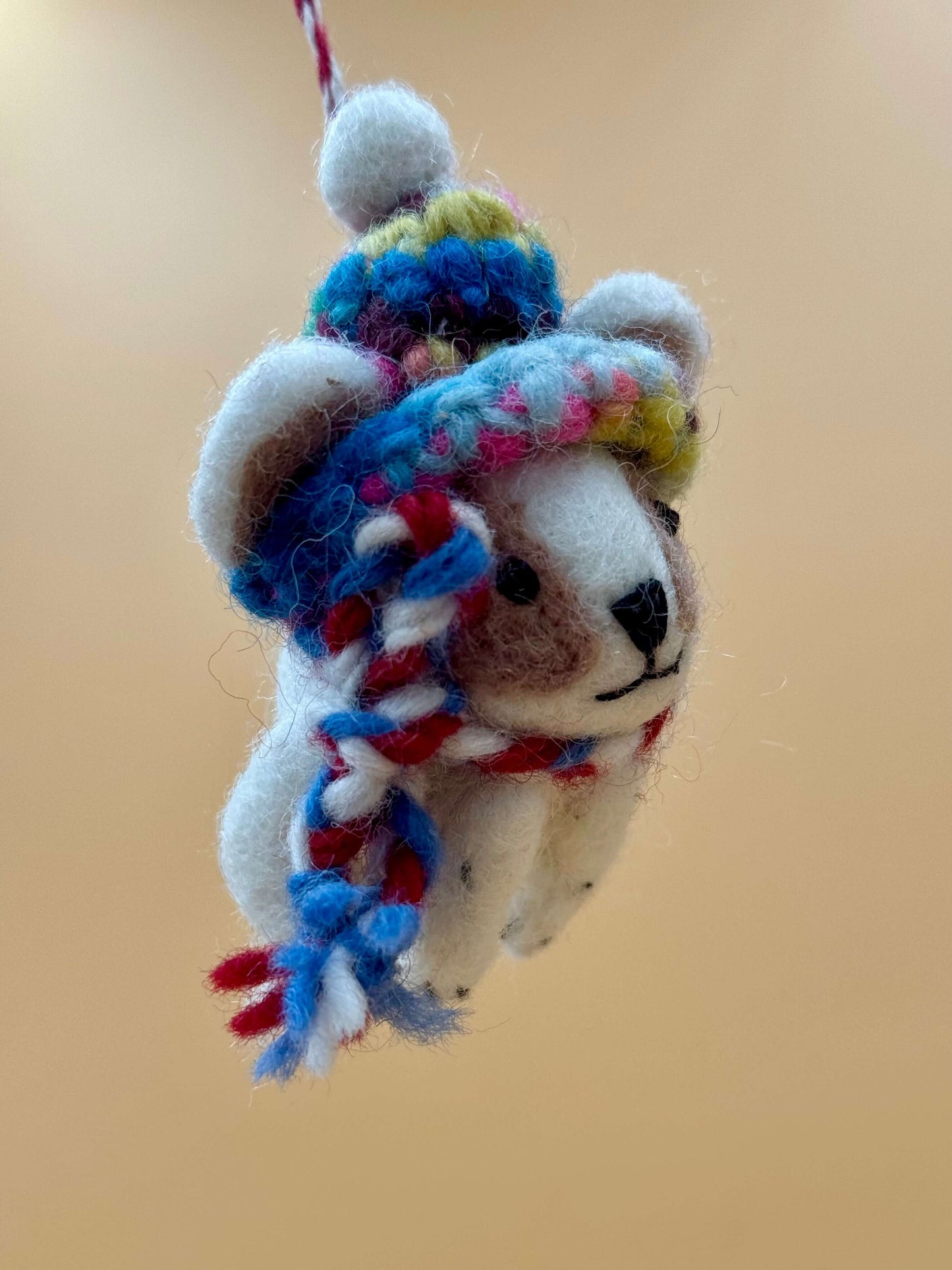 Handcrafted felt keychain of a cute dog wearing a hat and scarf, in brown and white wool. Unique accessory.