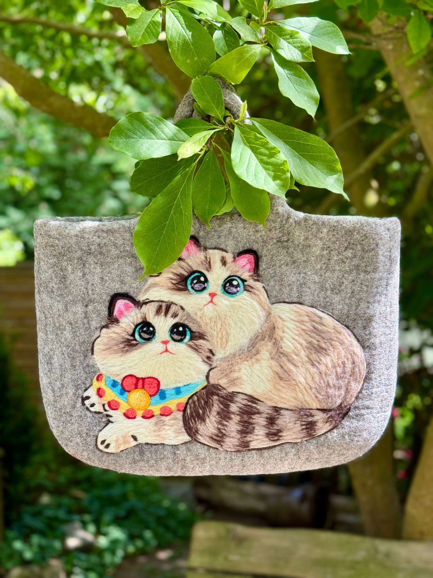 Handmade grey felt bag featuring two cute illustrated cats, perfect for carrying essentials.