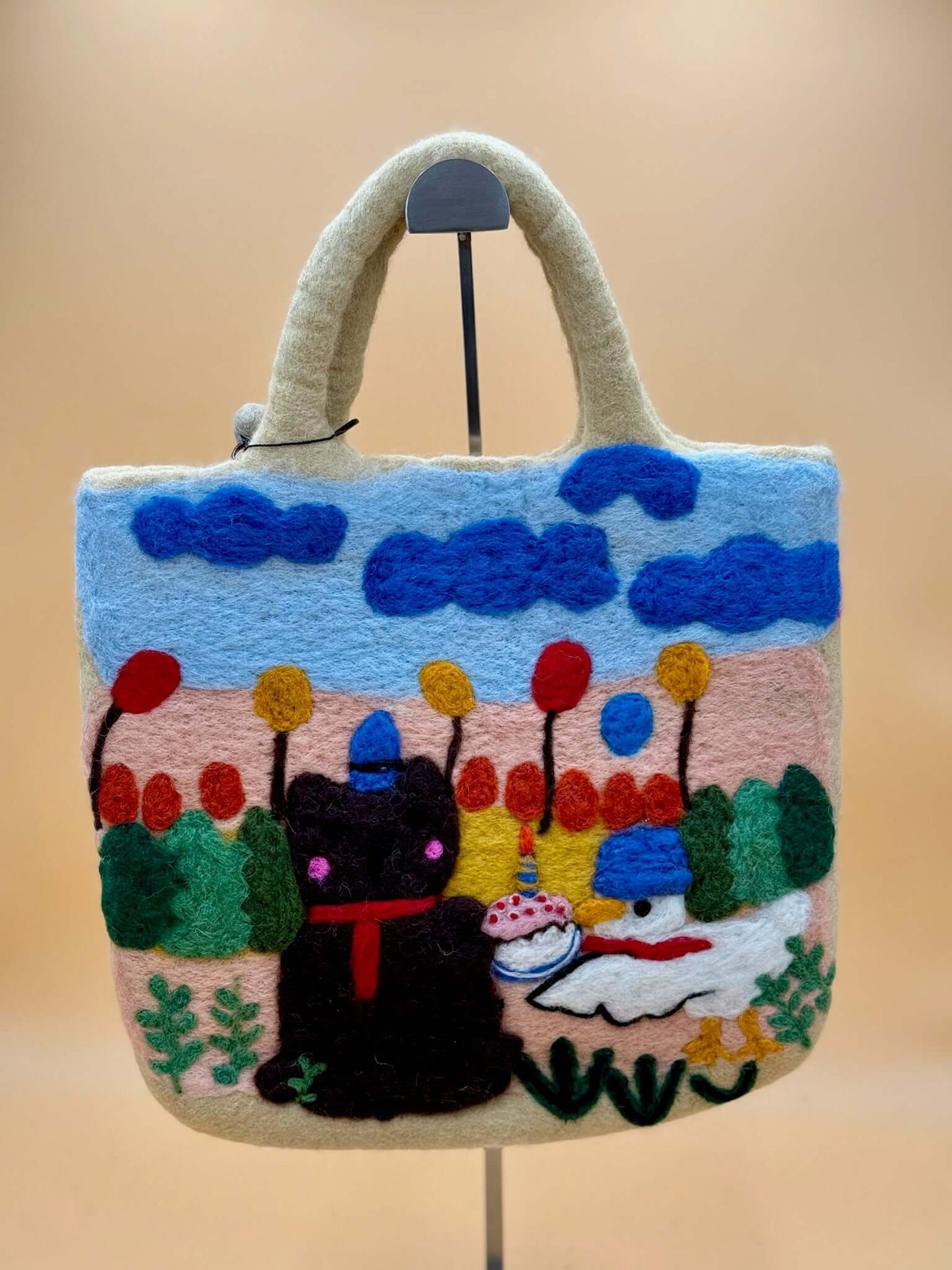 Handmade felt bag featuring a whimsical cat and colorful landscape design, perfect for carrying daily essentials.
