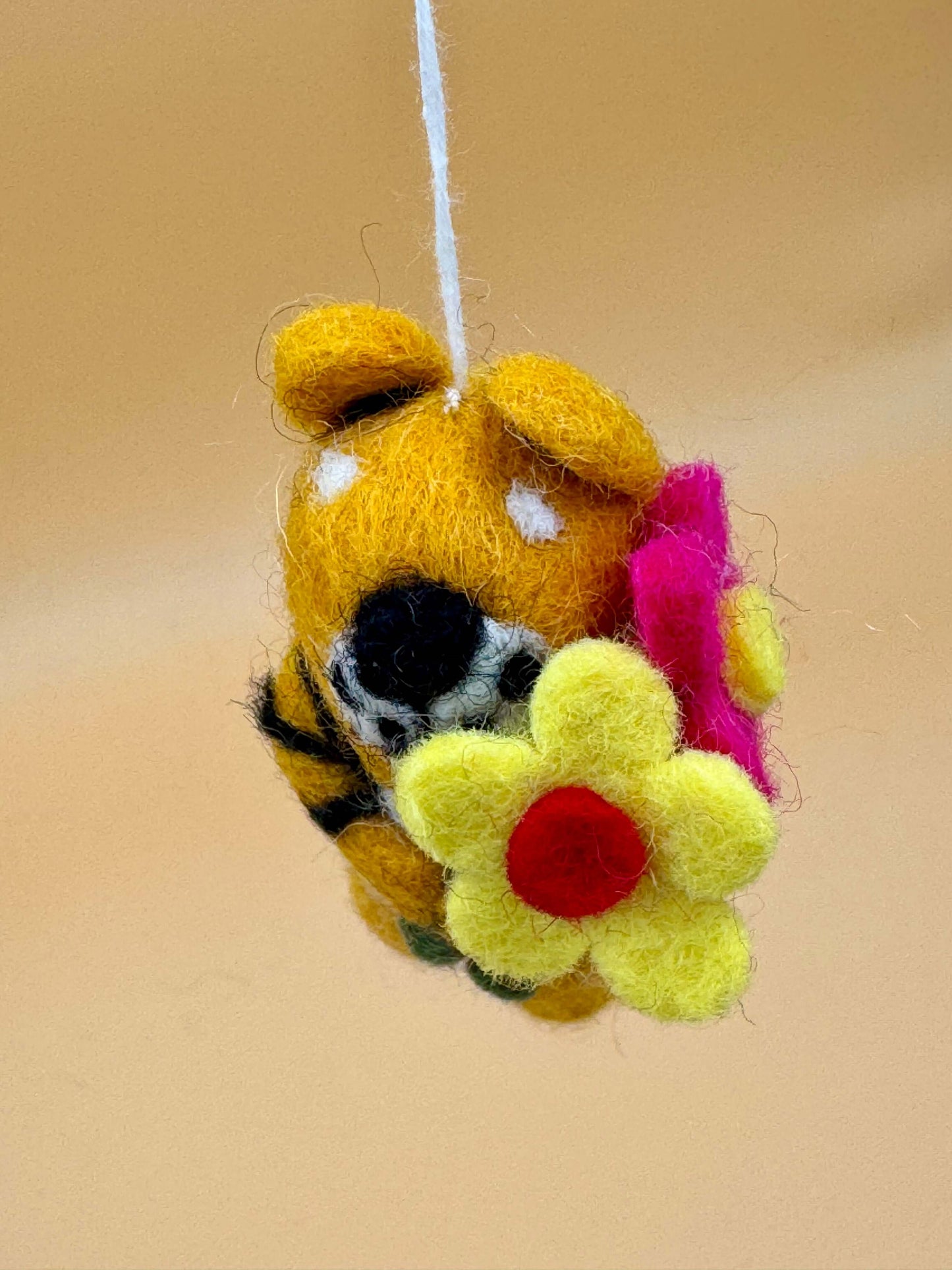 Handgemachter Filzanhänger Schlüsselanhänger Tiger mit bunten Blumen in Gelb, Schwarz und Rot.