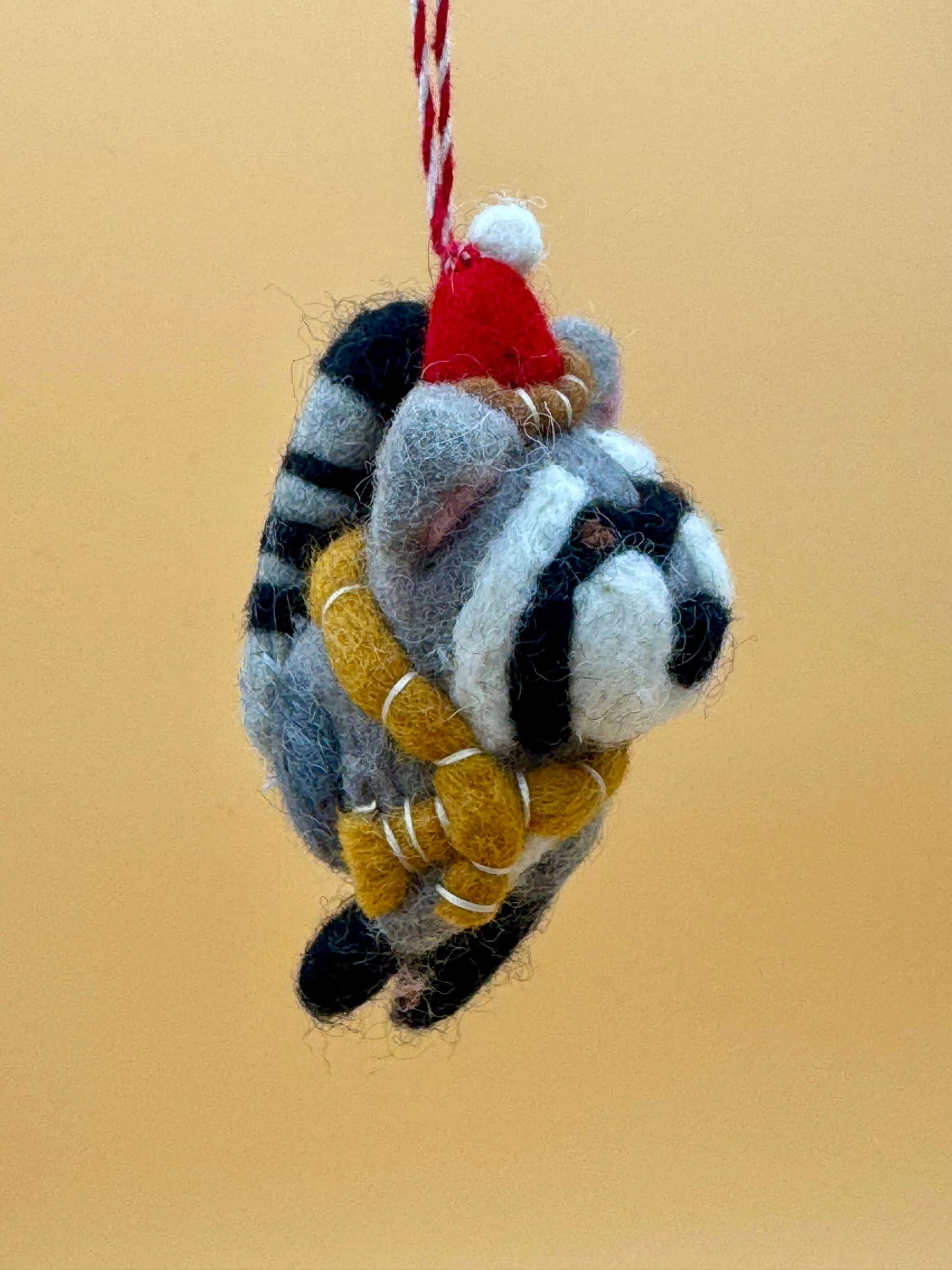 Filzanhänger Schlüsselanhänger Weihnachtswaschbär aus 100% Wolle in grau, schwarz und rot mit Schal und Mütze.