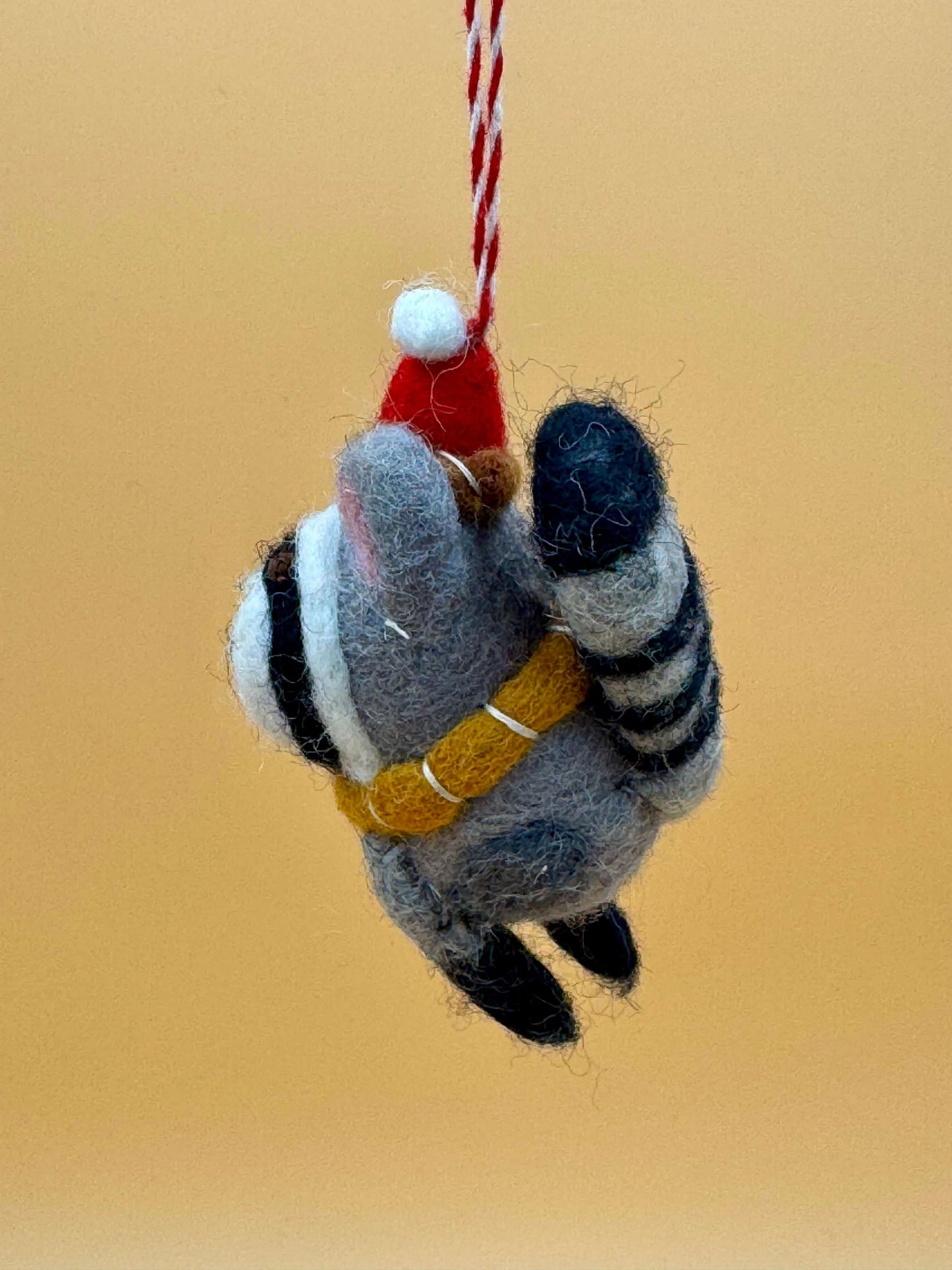 Handmade felt raccoon keychain ornament with a red hat, scarf, and unique design, perfect for Christmas decor.