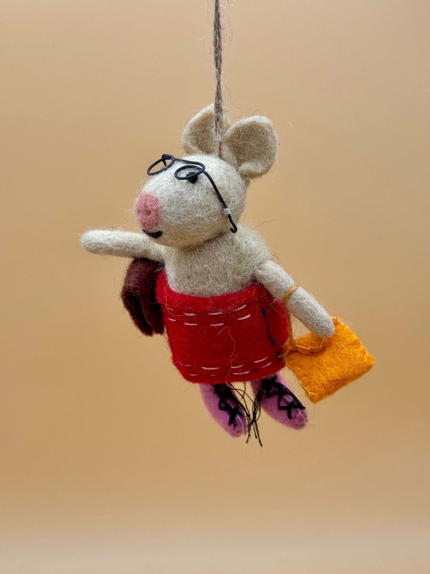 Handmade beige and red felt keychain featuring a stylish pig with glasses, holding a bag and book.