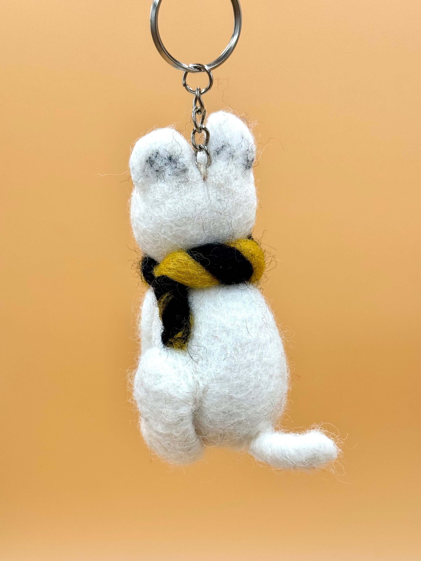 Handmade polar bear felt keychain with a black and yellow scarf, perfect for gifts or personal use.