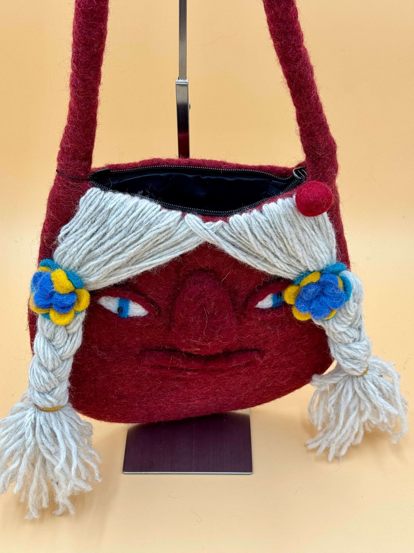 Handmade red felt shoulder bag Size M with unique face design, featuring wool trim and colors, ideal for carrying essentials.