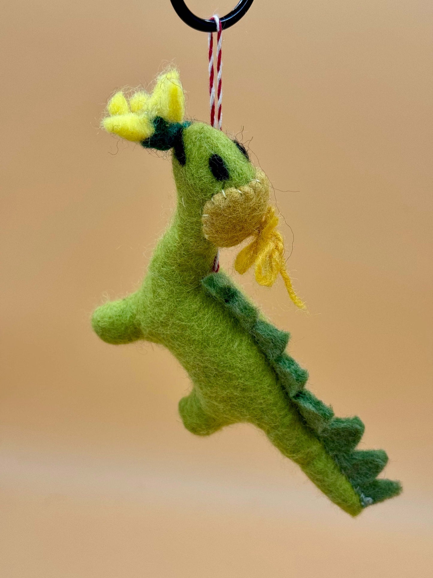 Handgemachter Filzanhänger Schlüsselanhänger Dino mit Blume in grün und gelb, einzigartiges Unikat aus 100% Wolle.