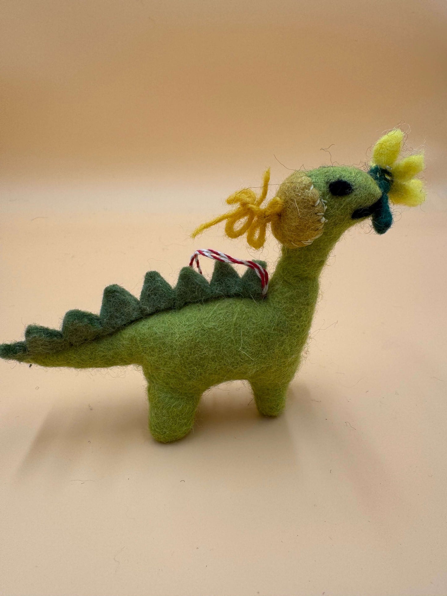 Filzanhänger Schlüsselanhänger Dino mit Blume, handgemacht aus 100% Wolle, grün mit gelber Blume, einzigartiges Design.