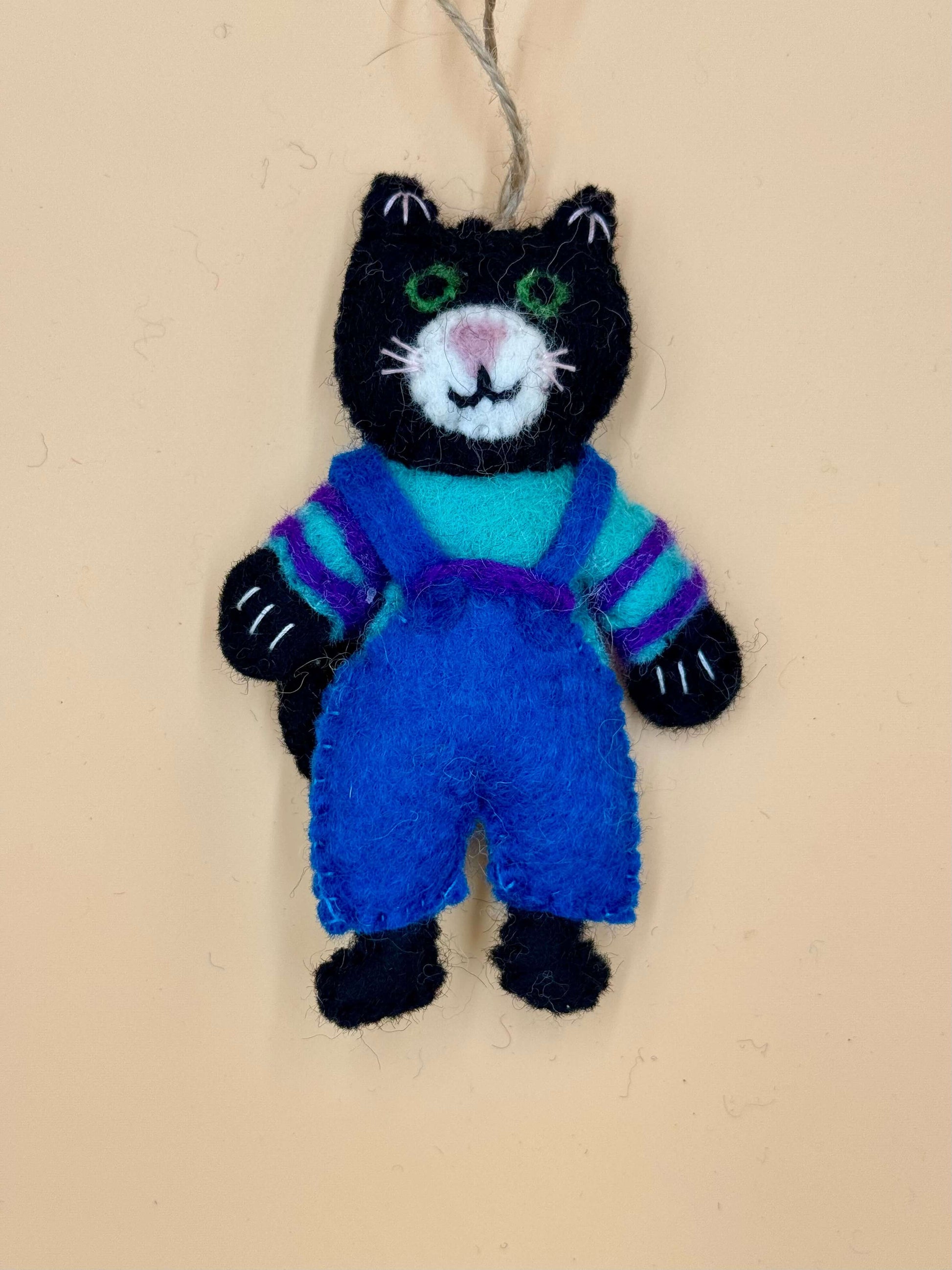 Handmade black cat keychain with blue overalls and colorful stripes, unique felt accessory.