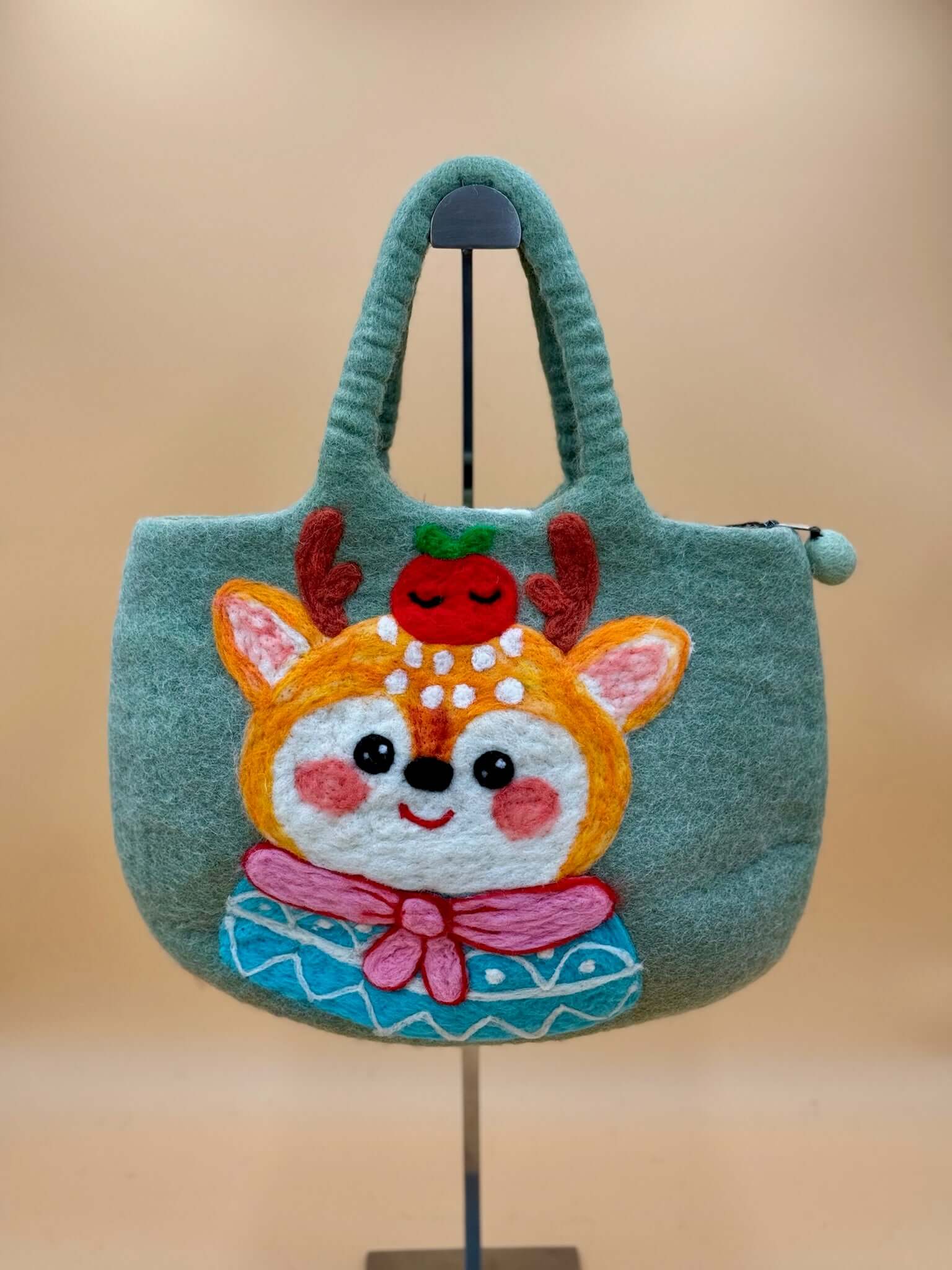 Handmade green felt tote bag with a cheerful deer design and apple on top, perfect for everyday use.