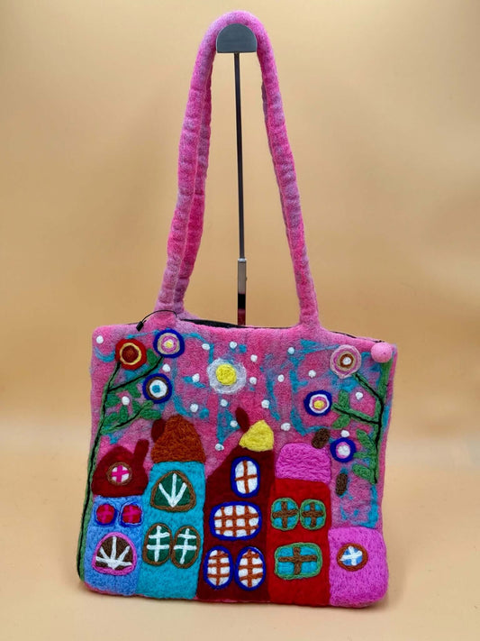 Handmade pink felt shoulder bag with colorful house design, perfect for carrying essentials.