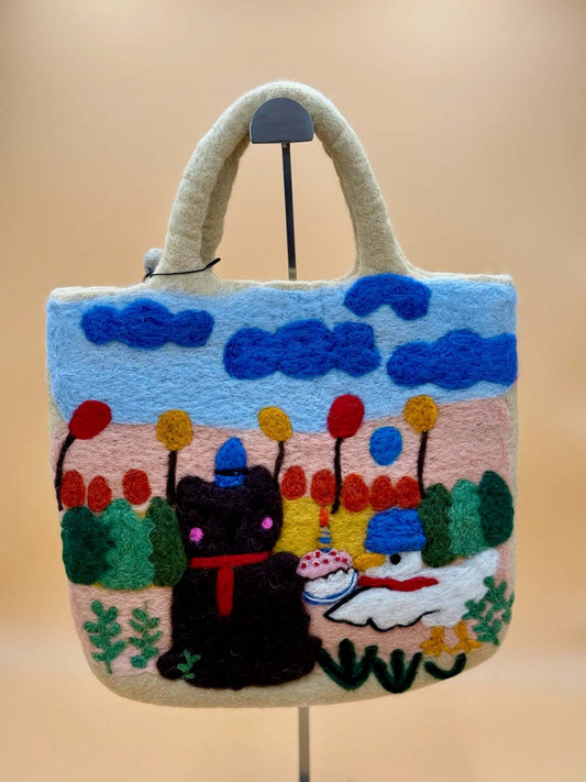 Handmade felt bag featuring a whimsical cat and colorful landscape design, perfect for carrying daily essentials.
