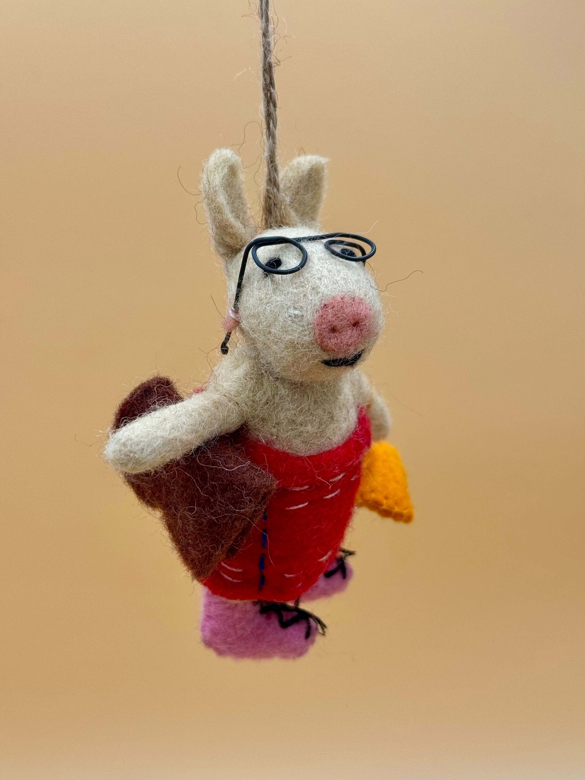 Handmade beige and brown felt pig keychain with glasses, dress, bag, and book. Unique felt accessory.